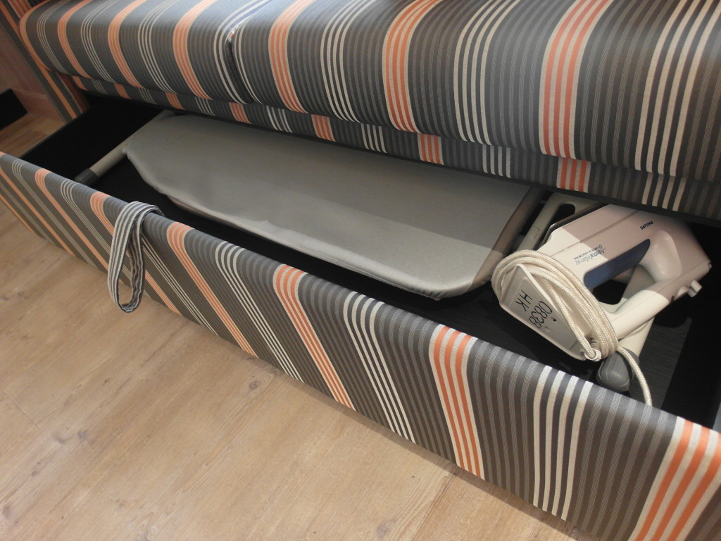 Ironing board and iron neatly stowed away beneath the sofa
