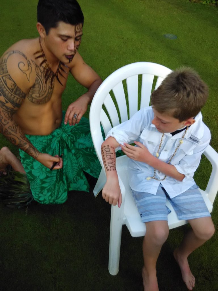 Staff doing a arm painting for a kid at Grand Hyatt Kauai Luau