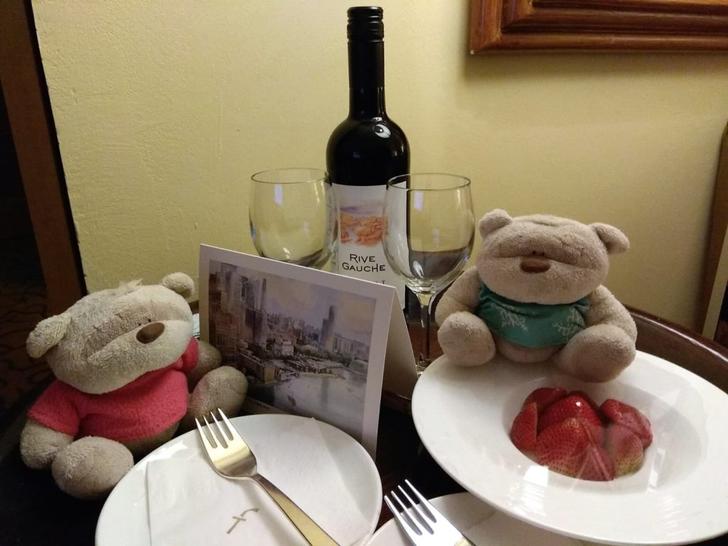 Bottle of wine, strawberries and postcard signed by the GM of the Fullerton Hotel Singapore