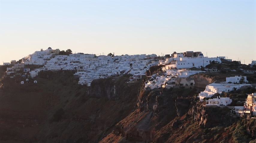 View of the next township - Imerovigli as the sun set, illuminating the white cave houses